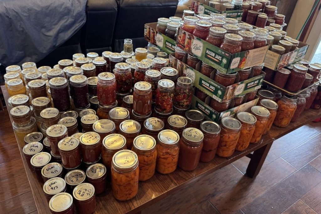 Table full of canned garden produce and fruit. Reasons we preserve food on our homestead.