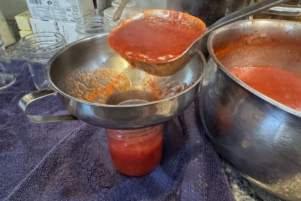 Filling my clean canning jars with hot jam.