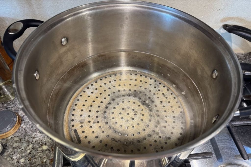 Fill stockpot with hot water, one of the steps in water bath canning.