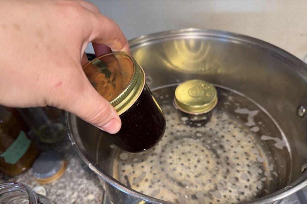 Placing the jam jars into hot water inside my water bath canner.